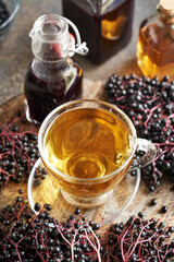 Sticker - A cup of tea with black elderberry syrup on a table