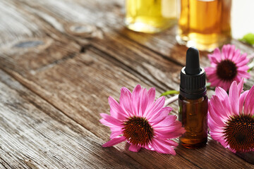 Wall Mural - A brown bottle of aromatherapy essential oil or tincture with purple echinacea flowers, with copy space