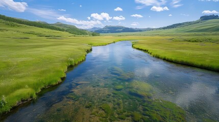 Aufkleber - A river runs through a grassy field. The water is clear and calm. The sky is blue and there are some clouds. The scene is peaceful and serene
