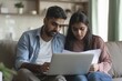 © Raool - Serious indian couple paying bills online, sitting on couch, using laptop, concentrated husband and wife checking papers and banking on Internet, copy, Generative AI
