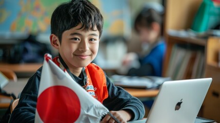 Poster - A cheerful young boy in a classroom smiles while holding a Japanese flag and working on his laptop.