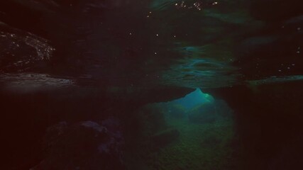 Wall Mural - Split level view in underwater cave to blue water with bright sun rays, Mediterranean Sea, Slow motion. Underwater seascape inside an underwater cave with sunlight 