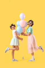 Wall Mural - Little girl and her mother with hair curlers holding balloons on yellow background