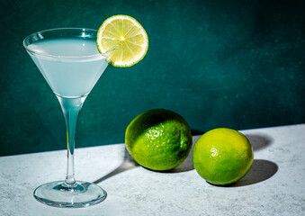 Wall Mural - Alcoholic cocktail with vodka, syrup, lime juice and ice in martini glass, dark green background