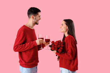 Wall Mural - Happy young couple with glasses of wine and roses on pink background. Valentine's Day celebration