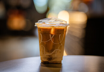 Close up and selective focus glass of ice latte on black table at coffee shop.