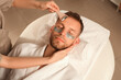 © Pixel-Shot - Handsome young man in under-eye patches receiving facial massage with roller in beauty salon