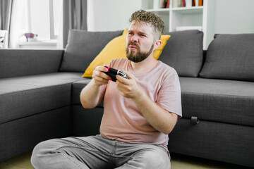 Man playing video games in living room sitting on sofa.