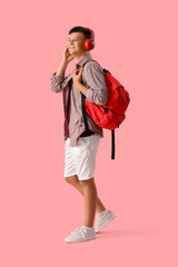 Wall Mural - Teenage boy in headphones with backpack on pink background