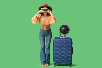 Sticker - Young Asian woman with globe and suitcase taking pictures on green background. Travel concept