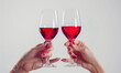 © hunter76 - Zadbane kobiece dłonie trzymające kieliszki czerwonego wina. Białe jednolite tło