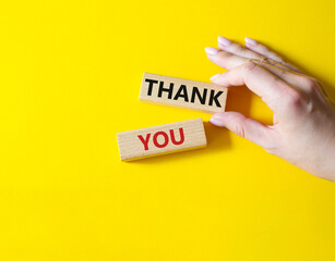 Wall Mural - Thank you symbol. Wooden blocks with words Thank you. Businessman hand. Beautiful yellow background. Business and Thank you concept. Copy space.