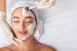 © Home-stock - Facial beauty treatment. Beautiful woman getting mask at spa salon, cosmetologist applying white mask with brush, top view, free space