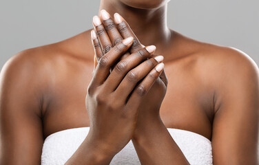 Wall Mural - Skin nutrition concept. Unrecognizable african american woman applying moisturizing cream to her hands over gray studio background, crop