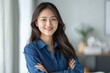 © darshika - Asian woman with long hair in blue shirt smiling.