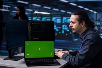 Poster - engineer working on isolated screen laptop in data center housing storage devices. man using mockup 