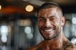 © Лена Шевчук - A fit muscular male personal trainer smiling at the camera in a gym, close up