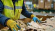 © Rufat - A man in a yellow vest and gloves sorts waste on a piece of cardboard promoting eco conscious practices