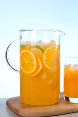 Wall Mural - Freshly made lemonade in jug and glass on table against light blue background