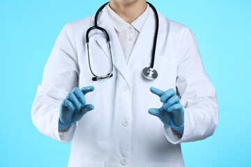 Wall Mural - Doctor holding something on light blue background, closeup