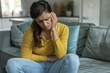 © Andrii - Woman Feeling Discomfort While Sitting on Couch in Modern Living Room