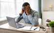© Prostock-studio - Stressful Job. Stressed African Businessman At Laptop Touching Head Having Problem At Workplace Sitting In Modern Office. Crisis And Entrepreneurship Business Issues, Headache Concept