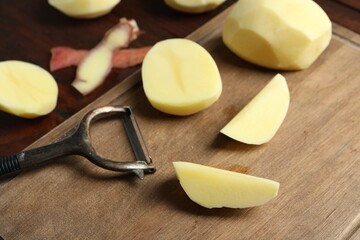 Wall Mural - Fresh raw potatoes, peels and peeler on table