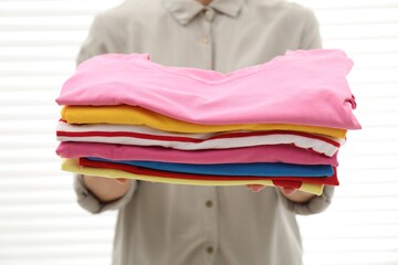 Sticker - Woman with stack of clean clothes indoors, closeup