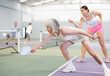 © JackF - Portrait of positive fit elderly woman playing pickleball on indoor court, swinging paddle to return ball over net ..