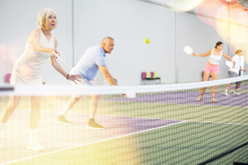 Wall Mural - Athletic seniors playing pickleball on the court indoors