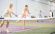 © JackF - Focused elderly woman playing friendly pickleball match in doubles team with young girl on indoors court. Sport and active lifestyle concept ..