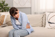 © New Africa - Upset woman suffering from abdominal pain on sofa at home