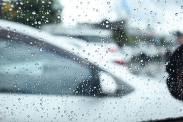 Wall Mural - water drop on mirror in defocused car parking background