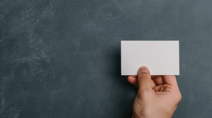 Close up shot of a white business card being held in a person s hand showcasing a minimalist and elegant design  The card has a plain blank surface with a deep depth of field