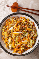 Wall Mural - Egg roll bowl with vegetables and meat traditional asian food in one pot close-up on table. Vertical top view from above