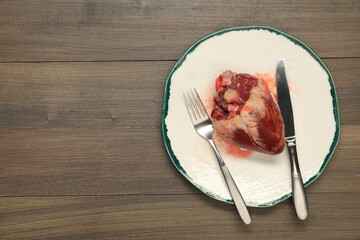 Wall Mural - Raw heart, fork and knife on wooden table, top view. Space for text