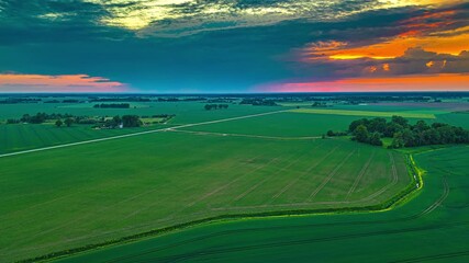 Wall Mural - dramatic clouds moving over rural fields, during sunset - aerial hyperlapse