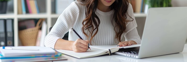 Aufkleber - Focused woman taking notes while studying at a desk in an office environment. She is using a laptop and has an open notebook, which creates a productive and professional atmosphere.