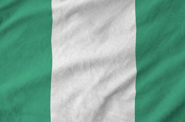 Wall Mural - Nigeria flag depicted on folded wavy fabric of old cloth close up