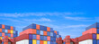 © Prapat - Group of many cargo containers stacked in terminal shipping yard area at commercial port against blue sky background in panoramic view, International shipping logistics backdrop