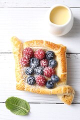 Wall Mural - Tasty puff pastry with berries on white wooden table, top view