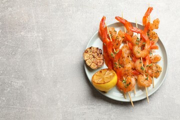 Wall Mural - Delicious grilled shrimp skewers, lemon and garlic on light grey table, top view. Space for text