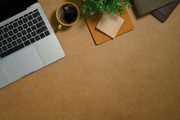 Fototapete - Simple workspace with cup of coffee, book and potted plant on brown background. Top view, flat lay