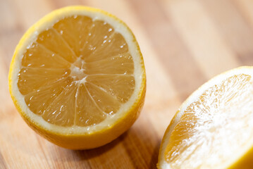 Close up shot of two halves of a lemon on wooden table. Yellow juicy sour lemon cut into halves, concept of vitamins in citrus