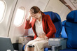 © NanSan - An Asian businesswoman travels abroad by plane,sitting near the window. She feels sick with air sickness, a stomach ache, headache, and neck pain during the long ride, but arrives at her destination.