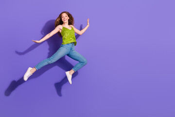 Full body photo of attractive teen woman running graceful dressed stylish green clothes isolated on violet color background