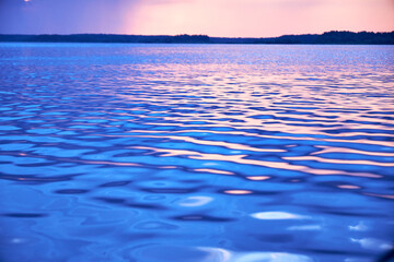 Wall Mural - blurred background view of summer sunset with the reflection of the sun on the river