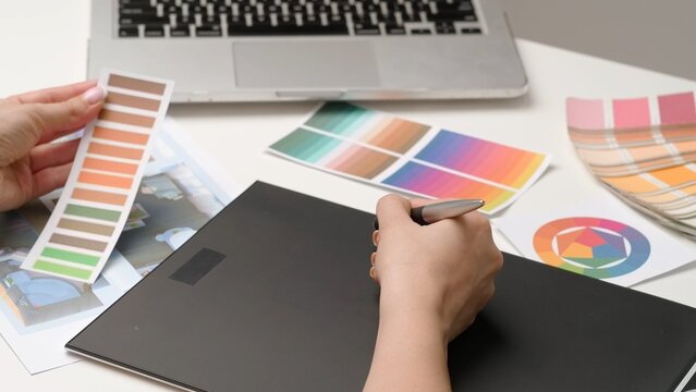 Woman interior designer works on digital graphic tablet with stylus, hand drawing home design project sketches. Creativity and modern technology.