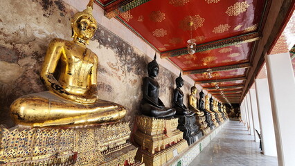 The gold buddha and black buddha statues inside Wat Suthat Thepwararam, Bangkok. Many sacred Buddha images are enshrined in an old church with beautiful designs. Buddha in meditation pose
