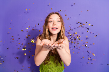 Sticker - Photo portrait of lovely teen lady hold blow confetti dressed stylish green garment isolated on violet color background